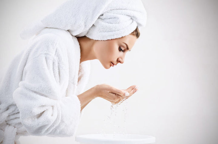 Young woman washing face with clean water.